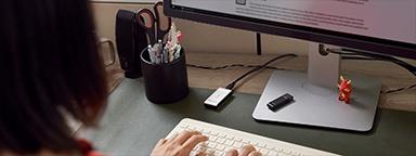 женщина печатает на клавиатуре с внешним твердотельным накопителем Kingston XS2000, подключенным к ее ПК