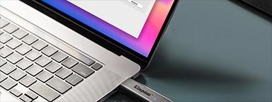 2 USB-накопителя DataTraveler Max, один из которых вставлен в ноутбук, а другой находится рядом с ним на столе
